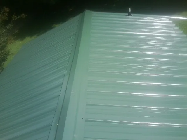 New green metal panels meeting at the ridge of a roof — Flat Roof Repair work by our crew in Ingleside
