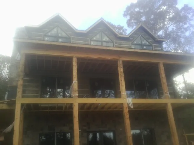 Dormers and porch framing on a large log home under construction — Roof Coating work by our crew in Ingleside