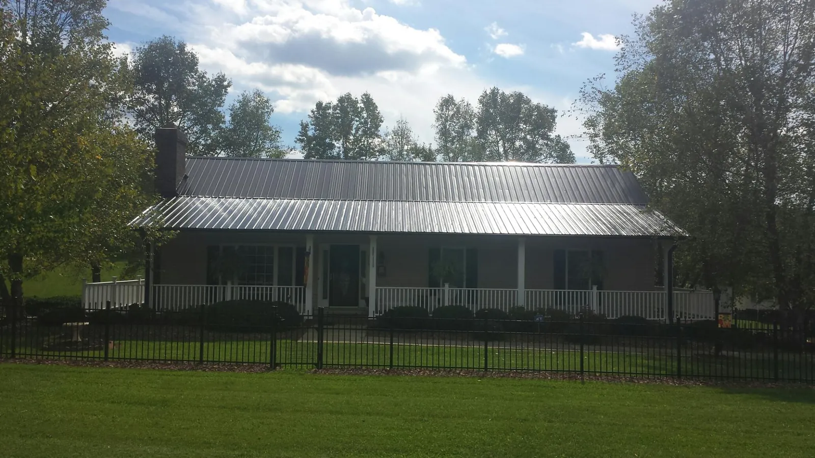 Gray metal roof on a brick ranch with a full width front porch — Gutter Guard Installation work by our crew in Ingleside